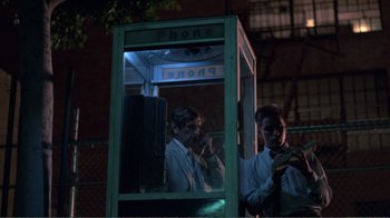 Movie still from “Repo Man” (1984), directed by Alex Cox – Two men are standing in a phone booth at night; Medium shot, Low angle