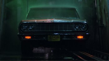 Movie still from “Repo Man” (1984), directed by Alex Cox – The front end of an old classic car in the dark; Wide shot, Low angle