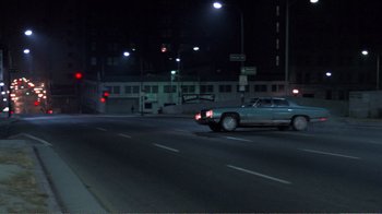 Movie still from “Repo Man” (1984), directed by Alex Cox – A car driving down a street at night; Extreme Wide shot, High angle