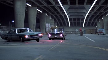Movie still from “Repo Man” (1984), directed by Alex Cox – A couple of cars driving down a street at night; Wide shot, Low angle