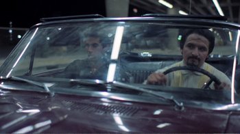 Movie still from “Repo Man” (1984), directed by Alex Cox – Two men in the back seat of a car; Medium shot, Over the shoulder angle