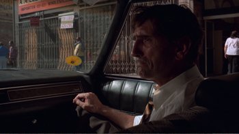 Movie still from “Repo Man” (1984), directed by Alex Cox – A man sitting in the driver's seat of a car; Medium shot, Over the shoulder angle