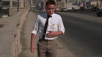 Movie still from “Repo Man” (1984), directed by Alex Cox – A man in a white dress shirt and a black tie standing on the side of a road; Medium shot, Low angle