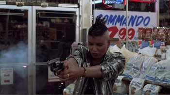 Movie still from “Repo Man” (1984), directed by Alex Cox – A person with a gun in a room; Medium shot, Low angle