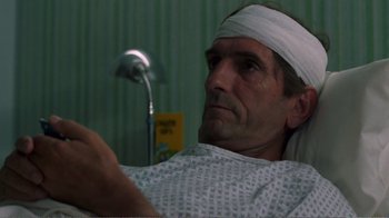 Movie still from “Repo Man” (1984), directed by Alex Cox – A man with a bandage on his head is in a hospital bed; Close Up shot, High angle