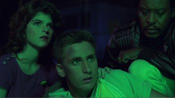 Movie still from “Repo Man” (1984), directed by Alex Cox – A man and a woman in a room lit up with green lights; Close Up shot, Low angle