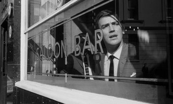 Movie still from “Repulsion” (1965), directed by Roman Polanski – A black - and - white photo of a man in a suit and tie; Medium shot, Low angle