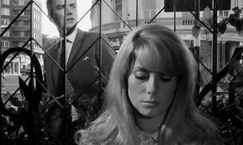 Movie still from “Repulsion” (1965), directed by Roman Polanski – A black - and - white photo of a woman in front of a man in a suit; Close Up shot, Low angle