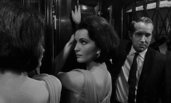 Movie still from “Repulsion” (1965), directed by Roman Polanski – Black and white photograph of a woman in front of two men; Medium shot, Over the shoulder angle