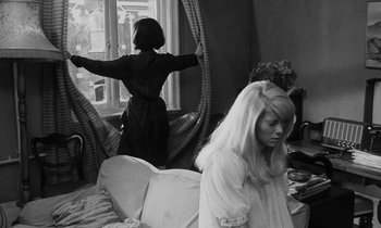 Movie still from “Repulsion” (1965), directed by Roman Polanski – A woman standing in front of a window and a woman sitting on a couch in front of a window; Medium shot, Over the shoulder angle