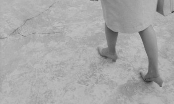 Movie still from “Repulsion” (1965), directed by Roman Polanski – A woman standing on a cement floor wearing a dress; Extreme Close Up shot, High angle