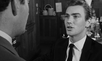 Movie still from “Repulsion” (1965), directed by Roman Polanski – A young man in a suit talking to another young man; Close Up shot, Over the shoulder angle