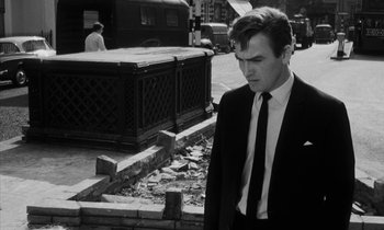 Movie still from “Repulsion” (1965), directed by Roman Polanski – A man in a suit and tie walking down a street; Medium shot, Low angle