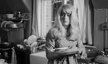 Movie still from “Repulsion” (1965), directed by Roman Polanski – A woman holding a plate of food in a kitchen; Medium shot, Over the shoulder angle