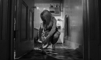 Movie still from “Repulsion” (1965), directed by Roman Polanski – A woman kneeling down in a kitchen looking at something on the floor; Medium shot, High angle