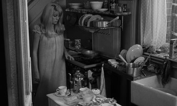 Movie still from “Repulsion” (1965), directed by Roman Polanski – A woman standing in front of a stove in a kitchen; Medium shot, High angle
