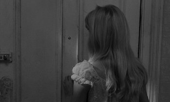 Movie still from “Repulsion” (1965), directed by Roman Polanski – A young girl in a white dress looking at a door; Close Up shot, Over the shoulder angle