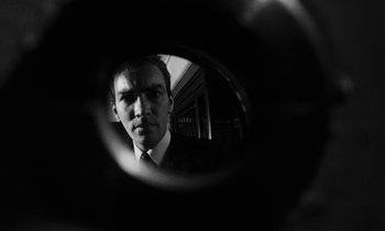 Movie still from “Repulsion” (1965), directed by Roman Polanski – A black and white photo of a man in a suit looking into a mirror; Extreme Close Up shot, Low angle