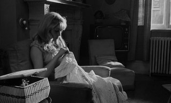 Movie still from “Repulsion” (1965), directed by Roman Polanski – A black and white photo of a woman sitting on a couch; Medium shot, High angle
