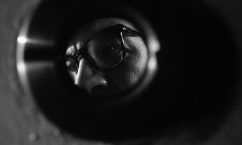 Movie still from “Repulsion” (1965), directed by Roman Polanski – A person wearing glasses looking into a mirror; Extreme Close Up shot, Low angle