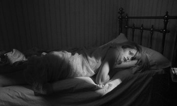 Movie still from “Repulsion” (1965), directed by Roman Polanski – A woman laying in a bed with a blanket on top of it; Medium shot, High angle