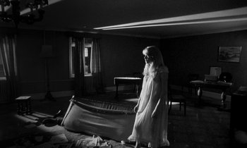 Movie still from “Repulsion” (1965), directed by Roman Polanski – A woman standing in front of an empty bed in a living room; Wide shot, High angle