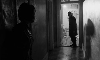 Movie still from “Repulsion” (1965), directed by Roman Polanski – A man and a woman are standing in a doorway; Wide shot, Over the shoulder angle