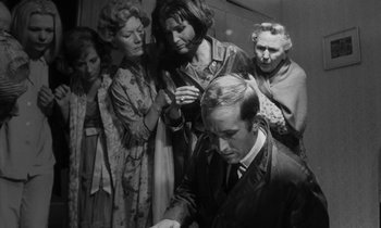 Movie still from “Repulsion” (1965), directed by Roman Polanski – An old photo of a group of people standing around a man; Medium shot, High angle