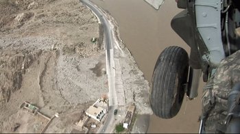 Movie still from “Restrepo” (2010), directed by Tim Hetherington – An aerial view of a road with a tire on the side of the road; Extreme Wide shot, Overhead angle