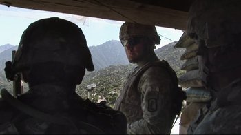 Movie still from “Restrepo” (2010), directed by Tim Hetherington – A man in military uniform standing next to another man in fatigues; Medium shot, Low angle