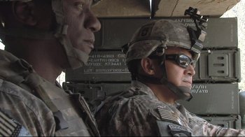 Movie still from “Restrepo” (2010), directed by Tim Hetherington – Two men in military uniforms are standing next to each other; Medium shot, Over the shoulder angle