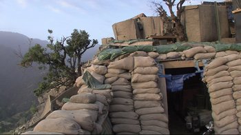 Movie still from “Restrepo” (2010), directed by Tim Hetherington – A pile of sandbags sitting on the side of a building; Wide shot, Low angle