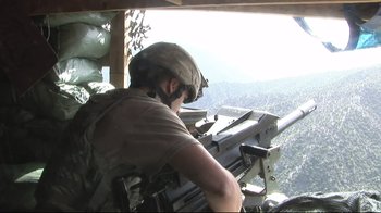 Movie still from “Restrepo” (2010), directed by Tim Hetherington – A man with a helmet on looking out of a helicopter window; Wide shot, Low angle