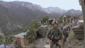 Movie still from “Restrepo” (2010), directed by Tim Hetherington – A group of soldiers walking across a dirt road; Wide shot, Low angle