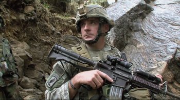 Movie still from “Restrepo” (2010), directed by Tim Hetherington – A man in camouflage holding a rifle in his hands; Close Up shot, Low angle