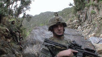 Movie still from “Restrepo” (2010), directed by Tim Hetherington – A man in a military uniform holding a rifle; Medium shot, Low angle
