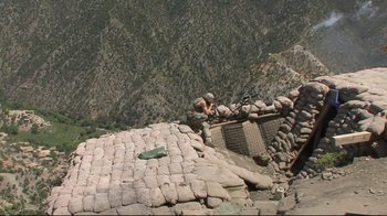Movie still from “Restrepo” (2010), directed by Tim Hetherington – A man in fatigues standing on top of a building; Extreme Wide shot, High angle