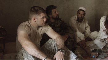 Movie still from “Restrepo” (2010), directed by Tim Hetherington – A group of men sitting next to each other in a room; Medium shot, Over the shoulder angle