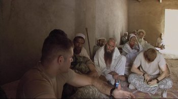 Movie still from “Restrepo” (2010), directed by Tim Hetherington – A group of men sitting in a room; Medium shot, High angle