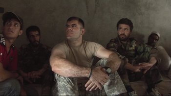 Movie still from “Restrepo” (2010), directed by Tim Hetherington – A group of men sitting next to each other in a room; Medium shot, Over the shoulder angle