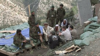 Movie still from “Restrepo” (2010), directed by Tim Hetherington – A group of men sitting on top of a hill; Wide shot, High angle