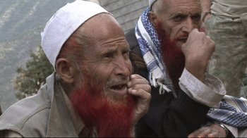 Movie still from “Restrepo” (2010), directed by Tim Hetherington – A man with a red beard is sitting next to another man with a red beard; Close Up shot, High angle