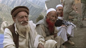 Movie still from “Restrepo” (2010), directed by Tim Hetherington – A group of men sitting next to each other on top of a hill; Medium shot, High angle