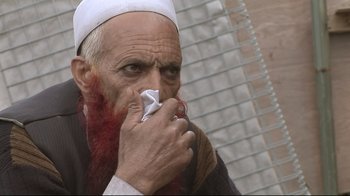 Movie still from “Restrepo” (2010), directed by Tim Hetherington – An old man with a beard and a white beard is holding a piece of paper; Extreme Close Up shot, High angle