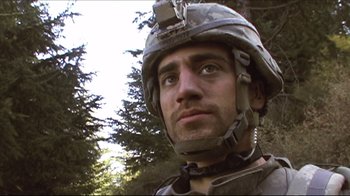 Movie still from “Restrepo” (2010), directed by Tim Hetherington – A man wearing a helmet is standing in front of a tree; Close Up shot, Low angle