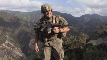 Movie still from “Restrepo” (2010), directed by Tim Hetherington – A man holding a rifle in his hand; Medium shot, Low angle