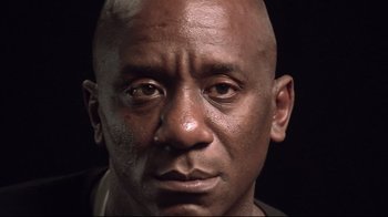 Movie still from “Restrepo” (2010), directed by Tim Hetherington – A man's face in a black background; Close Up shot, Low angle