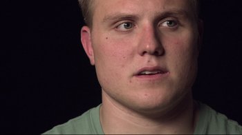 Movie still from “Restrepo” (2010), directed by Tim Hetherington – A man's face in a green t - shirt; Close Up shot, Low angle