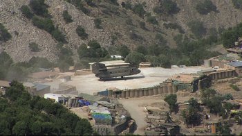 Movie still from “Restrepo” (2010), directed by Tim Hetherington – A military plane sitting on top of a dirt field; Extreme Wide shot, High angle