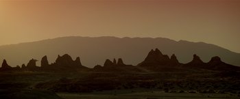 Movie still from “Revenge” (1990), directed by Tony Scott – A view of a mountain range at sunset; Extreme Wide shot, Low angle